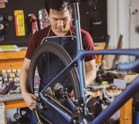 Young Asian business owner working in a bike shop with an apron on