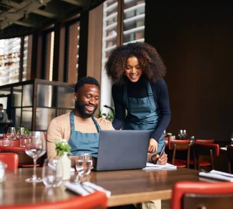 Young black couple of business owners looking at computer to track small business financial KPIs